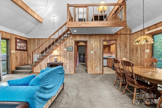 carpeted dining space with wooden walls and high vaulted ceiling