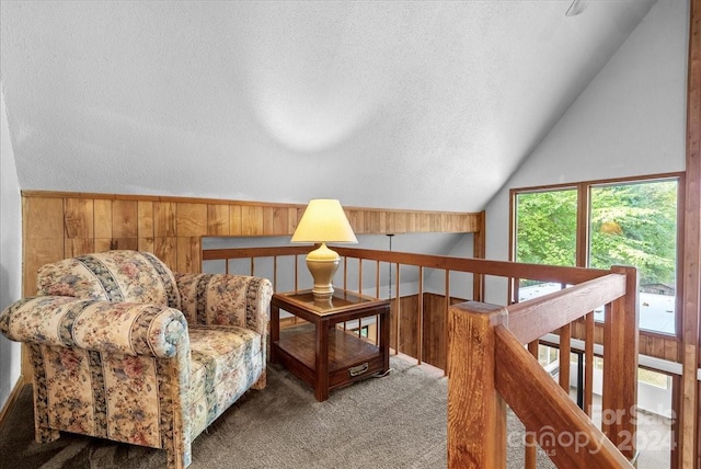 sitting room with wood walls, a textured ceiling, vaulted ceiling, and carpet