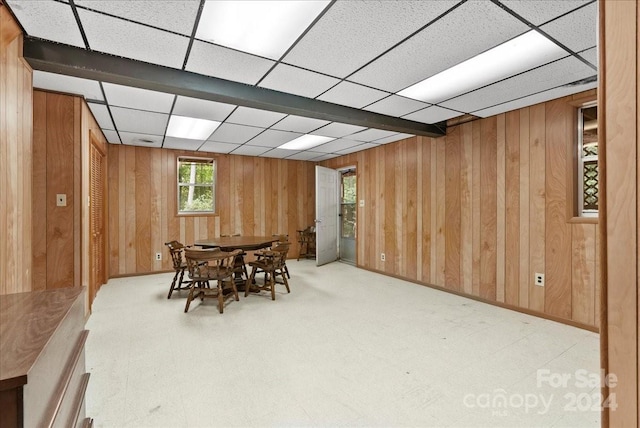 dining room featuring wood walls and a paneled ceiling