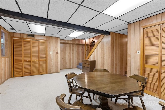 dining area with a drop ceiling and wood walls