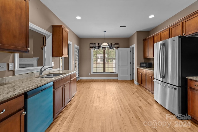 kitchen featuring sink, hanging light fixtures, light hardwood / wood-style flooring, light stone countertops, and stainless steel appliances