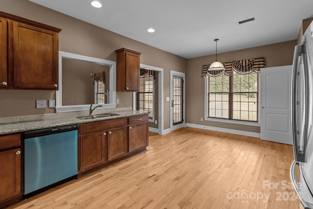 kitchen featuring sink, stainless steel appliances, light stone counters, decorative light fixtures, and light wood-type flooring