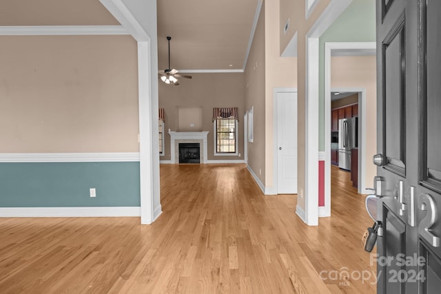 foyer featuring ceiling fan, crown molding, a high ceiling, and light wood-type flooring