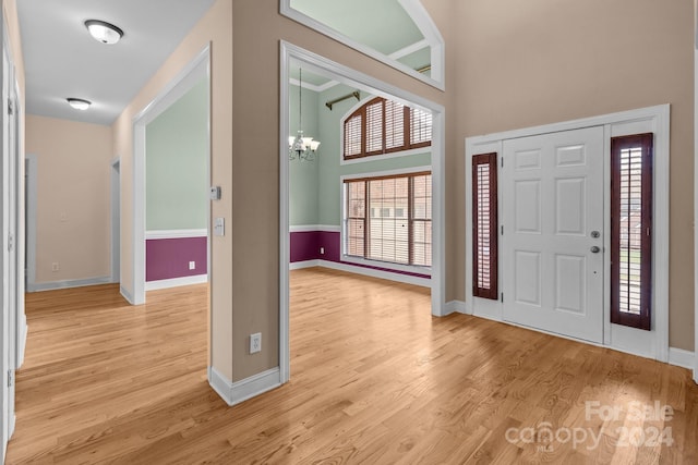 entrance foyer featuring a high ceiling, an inviting chandelier, and light hardwood / wood-style flooring