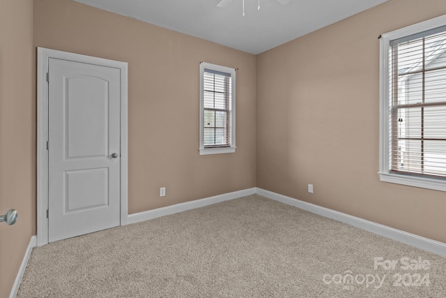 carpeted empty room featuring ceiling fan and plenty of natural light