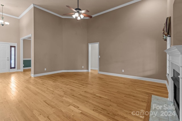 unfurnished living room featuring crown molding, a towering ceiling, and light hardwood / wood-style floors