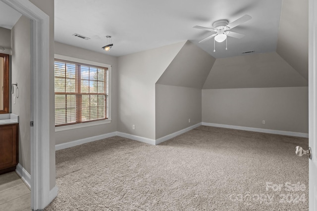 additional living space featuring light colored carpet, vaulted ceiling, and ceiling fan