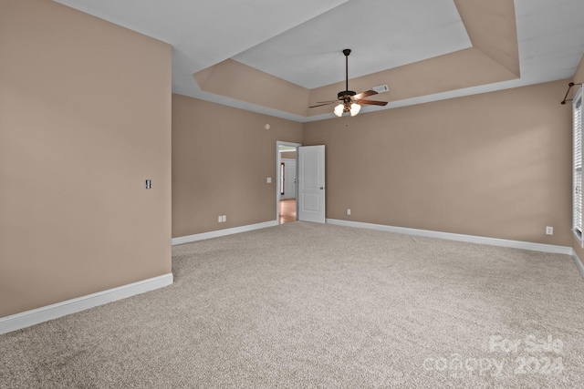 carpeted empty room with ceiling fan and a tray ceiling