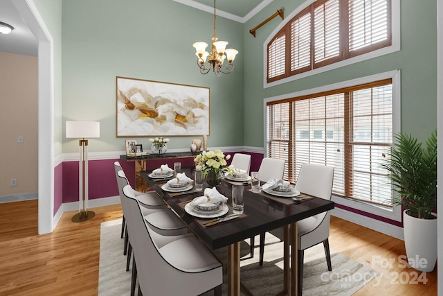 dining area with crown molding, a healthy amount of sunlight, light wood-type flooring, and a notable chandelier