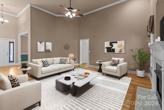 living room with a high ceiling, ceiling fan with notable chandelier, ornamental molding, and hardwood / wood-style floors