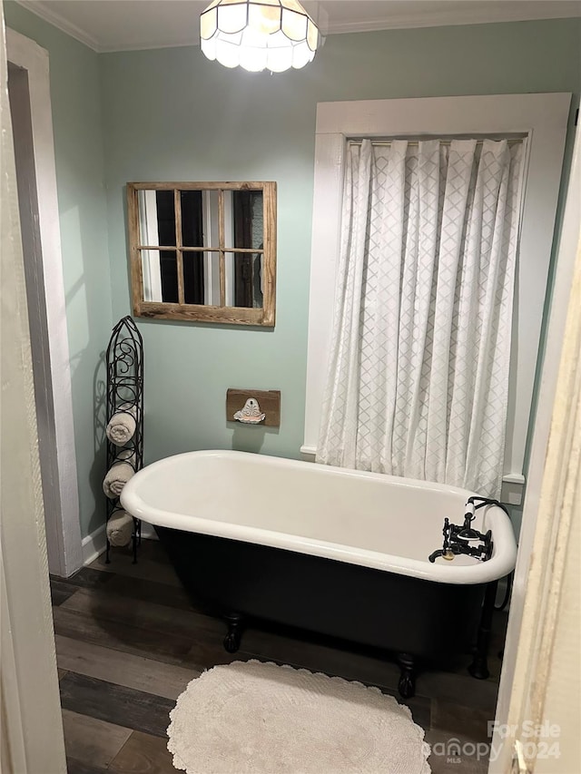 bathroom featuring hardwood / wood-style floors, a tub, and ornamental molding