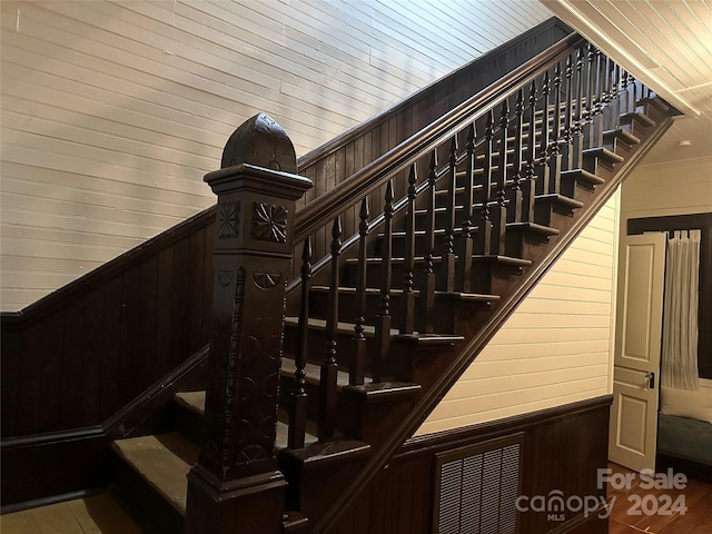 staircase with wood walls, hardwood / wood-style floors, and wood ceiling