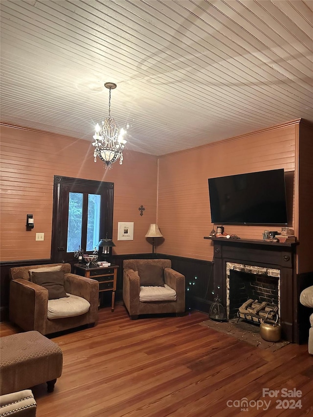 living room with hardwood / wood-style floors, an inviting chandelier, wood ceiling, and wood walls