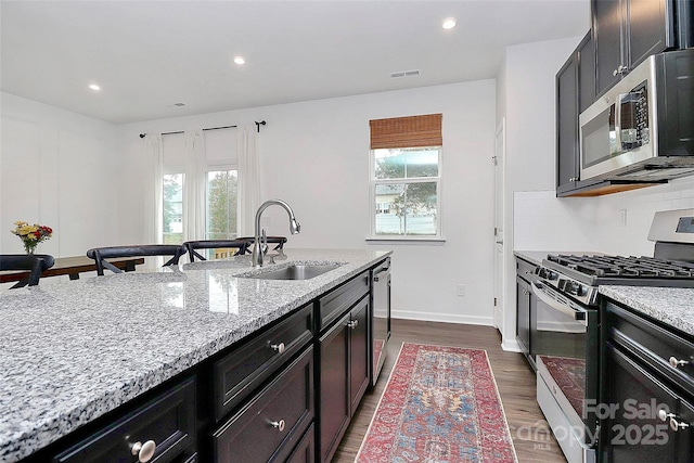 kitchen featuring sink, backsplash, light stone counters, stainless steel appliances, and a healthy amount of sunlight