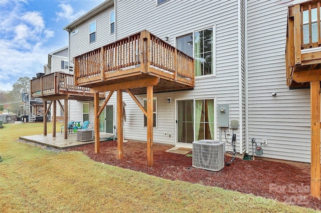 rear view of property featuring a wooden deck, a lawn, central AC unit, and a patio area