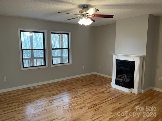 unfurnished living room with light wood-type flooring, a textured ceiling, and ceiling fan