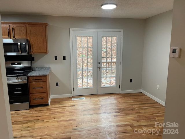 entryway with light wood-type flooring, french doors, and a textured ceiling