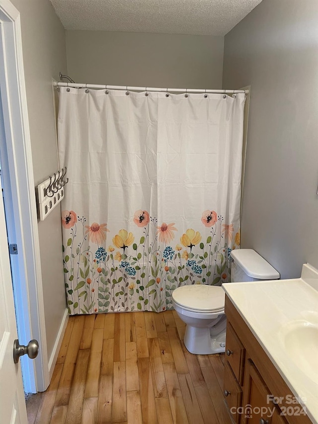 bathroom featuring vanity, wood-type flooring, a textured ceiling, and toilet