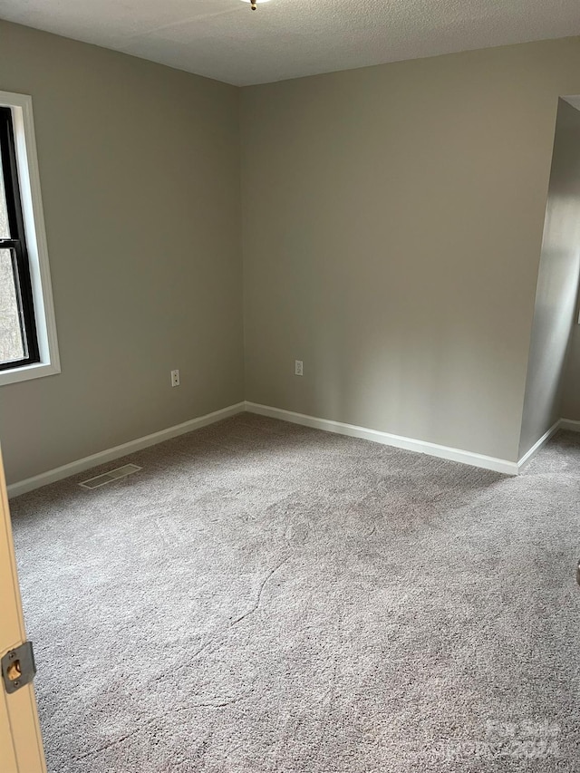 carpeted empty room with a textured ceiling