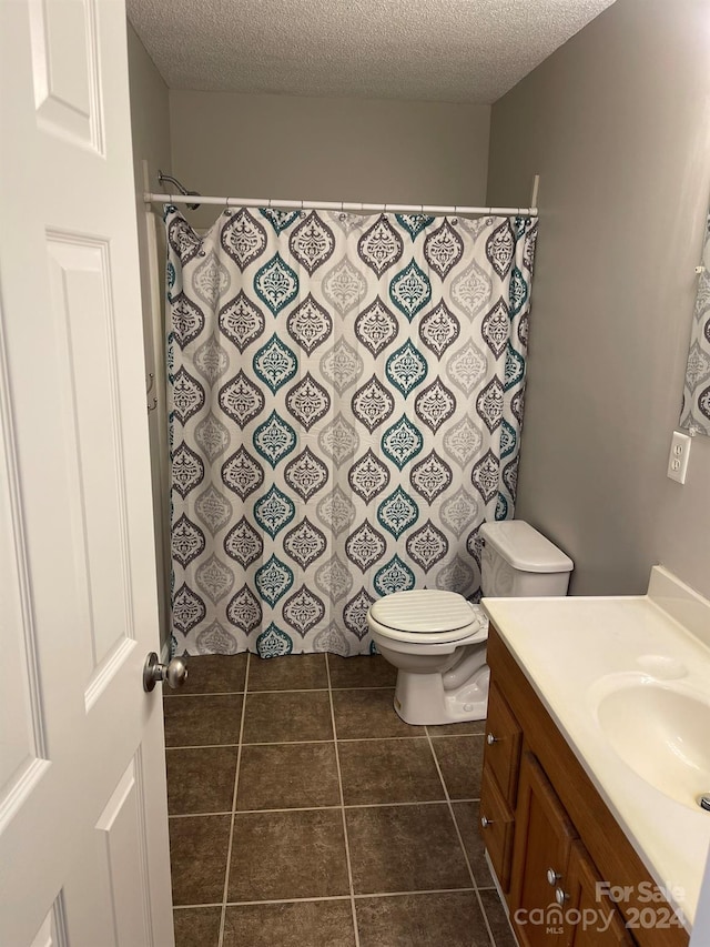 bathroom with tile patterned floors, vanity, a textured ceiling, and toilet