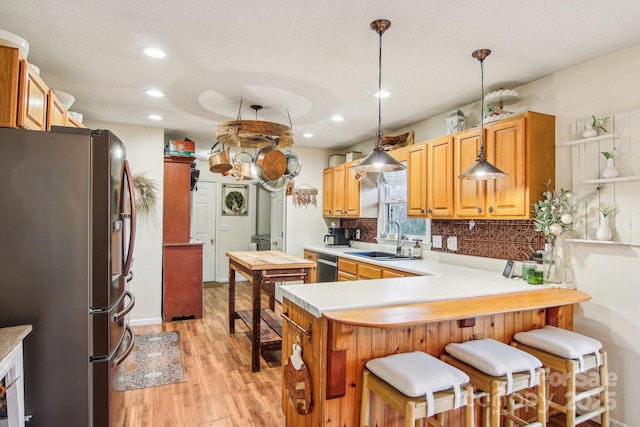 kitchen with sink, a breakfast bar area, stainless steel appliances, decorative light fixtures, and kitchen peninsula