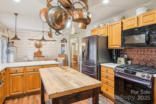 kitchen featuring butcher block countertops, backsplash, hanging light fixtures, stainless steel appliances, and light wood-type flooring