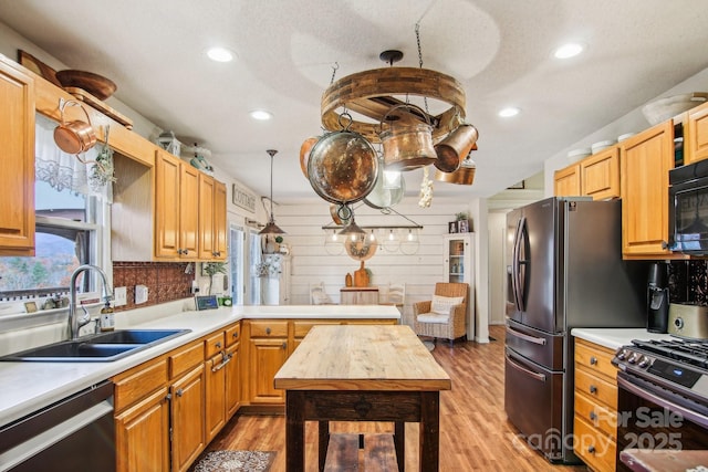 kitchen with sink, appliances with stainless steel finishes, pendant lighting, light hardwood / wood-style floors, and decorative backsplash