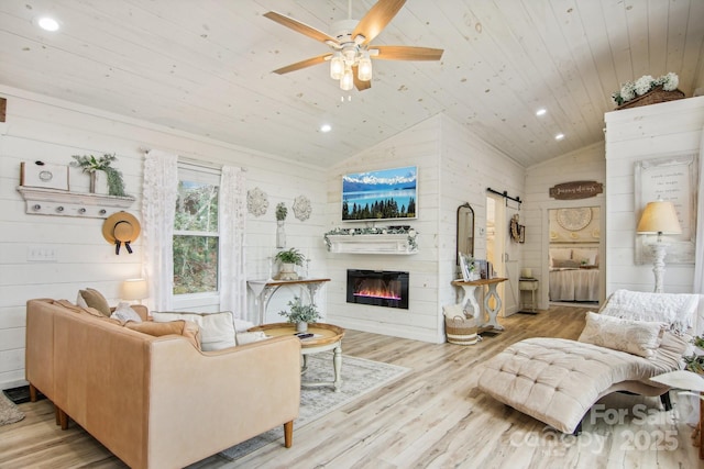 living room featuring vaulted ceiling, ceiling fan, wood ceiling, a barn door, and light hardwood / wood-style flooring