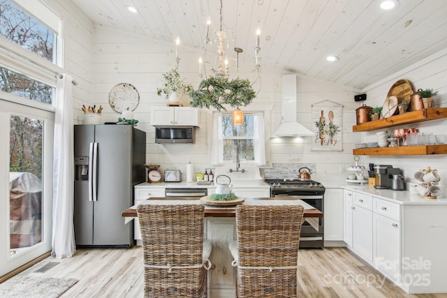 kitchen featuring wood ceiling, white cabinets, stainless steel appliances, and wall chimney range hood