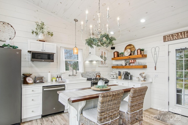 kitchen with appliances with stainless steel finishes, pendant lighting, white cabinetry, sink, and custom exhaust hood