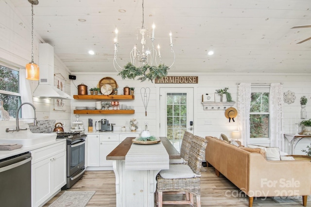 kitchen with sink, white cabinetry, decorative light fixtures, light wood-type flooring, and appliances with stainless steel finishes