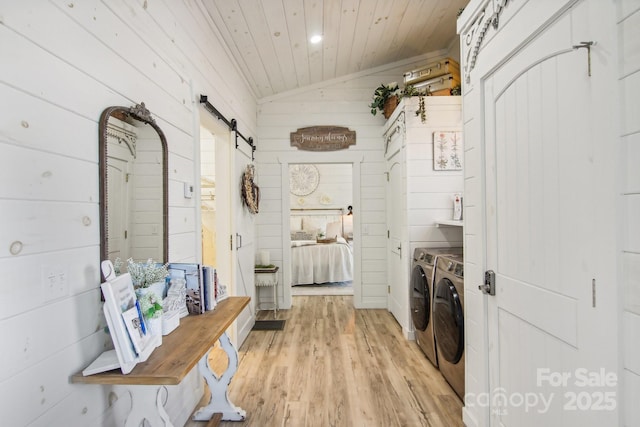 washroom with wood ceiling, separate washer and dryer, light wood-type flooring, wooden walls, and a barn door