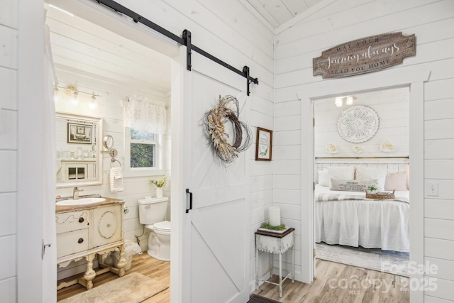 bathroom with hardwood / wood-style flooring, vanity, toilet, and vaulted ceiling