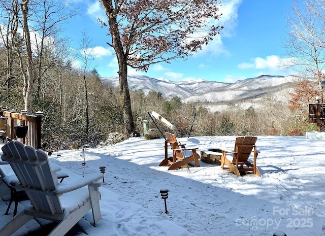 yard layered in snow with a mountain view and an outdoor fire pit