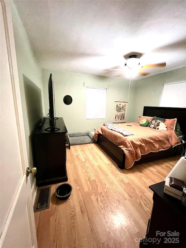 bedroom featuring hardwood / wood-style floors, a textured ceiling, and ceiling fan