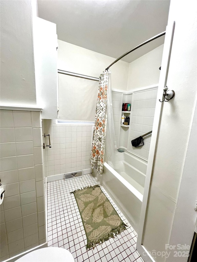 bathroom with toilet, shower / bath combo with shower curtain, tile walls, and tile patterned flooring