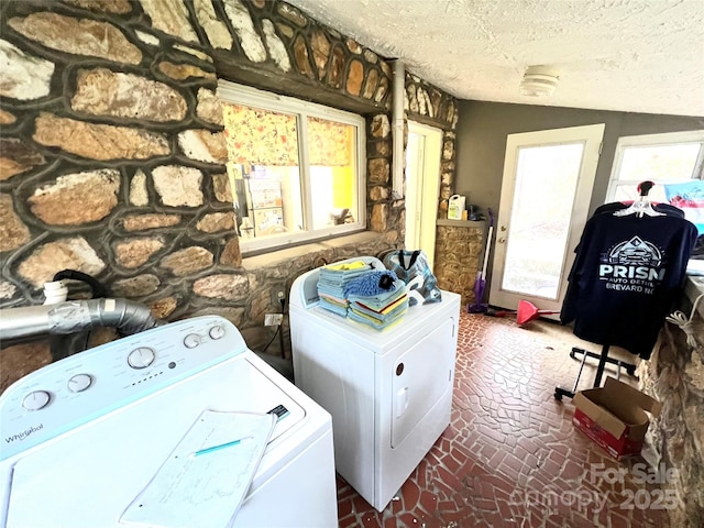 clothes washing area featuring independent washer and dryer, a textured ceiling, and a wealth of natural light