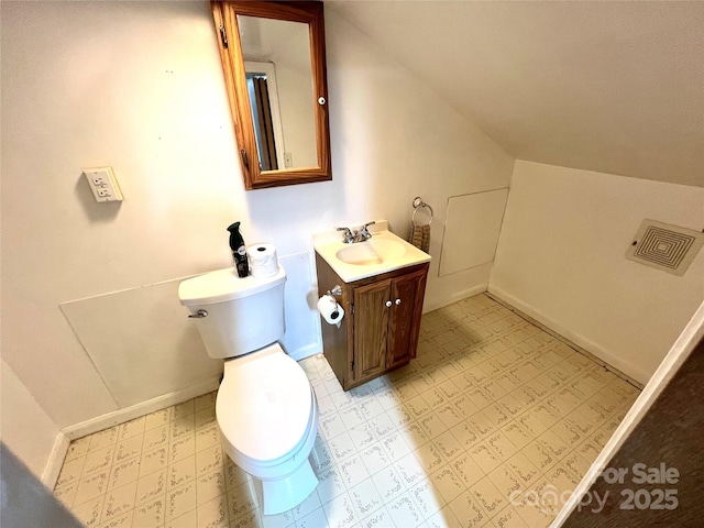 bathroom featuring vanity, lofted ceiling, and toilet