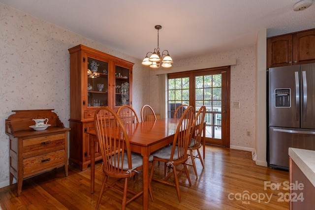 dining space with an inviting chandelier, hardwood / wood-style floors, and french doors