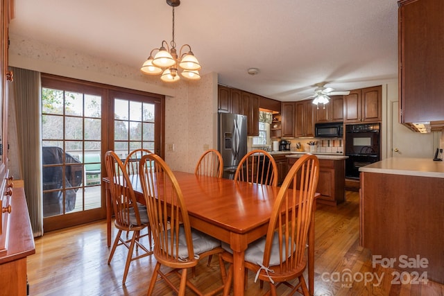 dining space with ceiling fan with notable chandelier and light hardwood / wood-style flooring