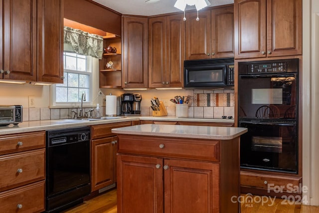 kitchen with black appliances, sink, light hardwood / wood-style floors, ceiling fan, and a center island