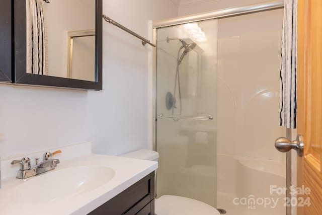 bathroom with walk in shower, vanity, and toilet