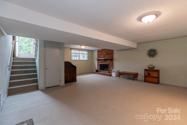 basement with a textured ceiling, a fireplace, a wealth of natural light, and light carpet