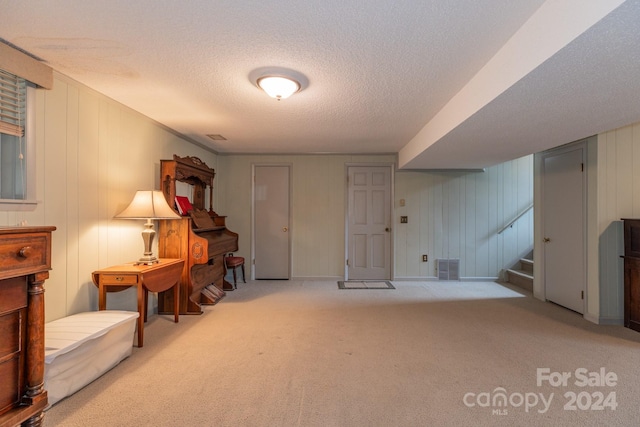 living area featuring wood walls, a textured ceiling, and light carpet