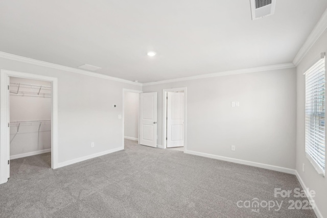 unfurnished bedroom featuring ornamental molding, a walk in closet, light colored carpet, and a closet