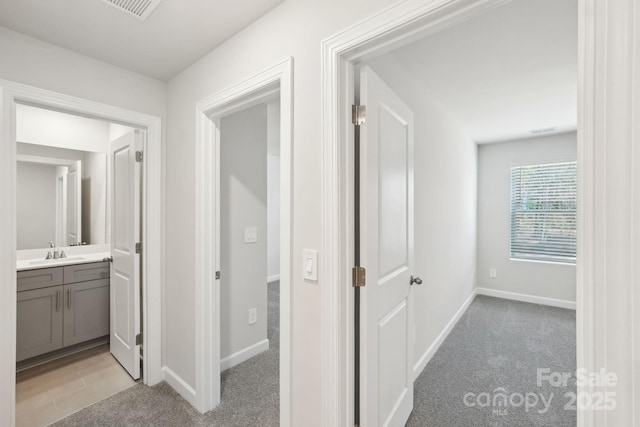 hallway featuring sink and light carpet