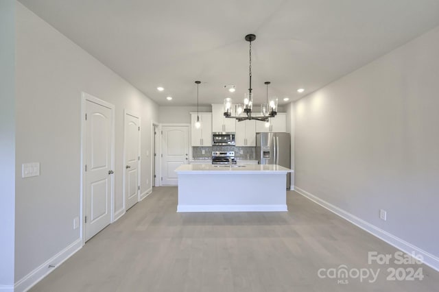 kitchen with decorative backsplash, an island with sink, decorative light fixtures, white cabinetry, and stainless steel appliances