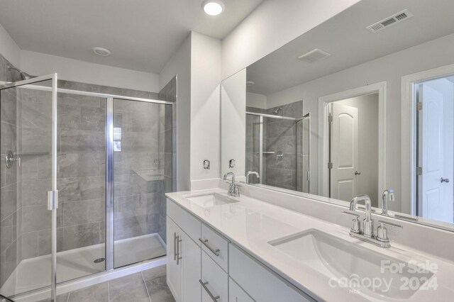 bathroom with tile patterned floors, vanity, and a shower with door