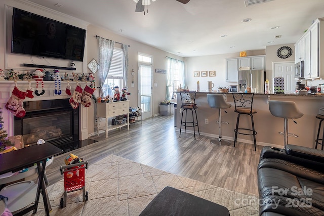 kitchen with kitchen peninsula, a breakfast bar, stainless steel appliances, light hardwood / wood-style floors, and white cabinetry