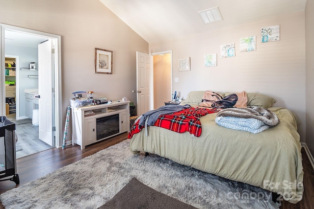 bedroom with connected bathroom, dark hardwood / wood-style floors, and vaulted ceiling